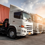 A row of white commercial trucks and a red container truck parked at a transport yard in South Africa, representing fleet and transport insurance cover